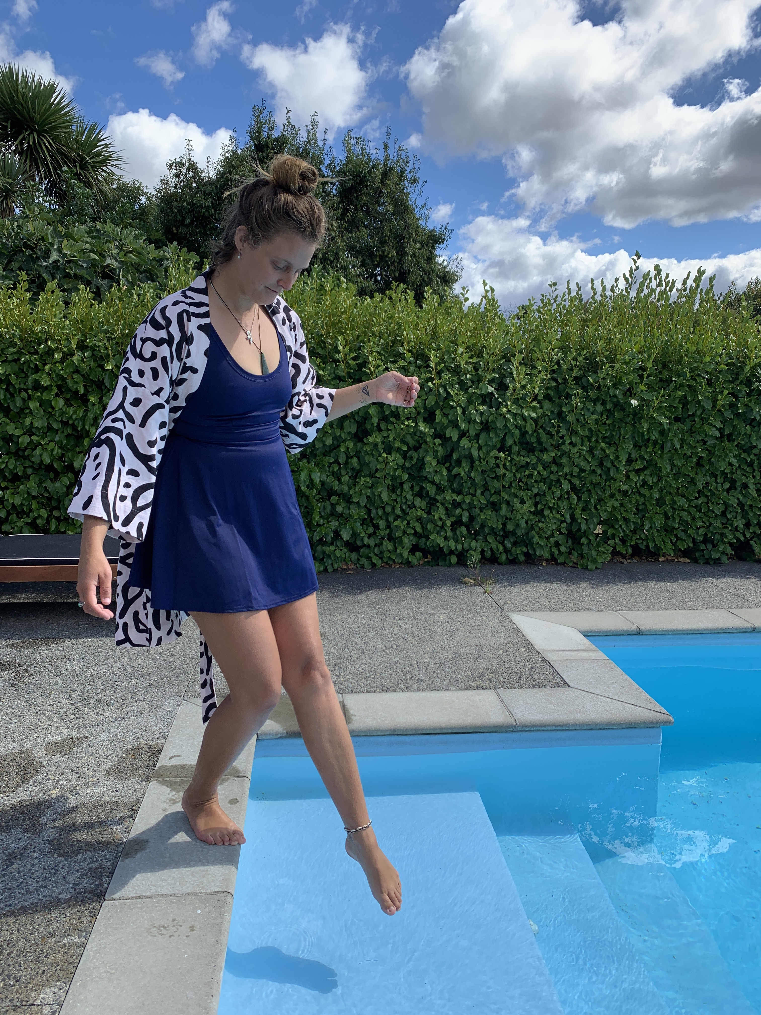 Navy Flared Swim Dress on person dipping toes in a pool