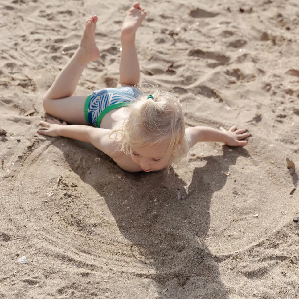 Young child playing in sand wearing underpants